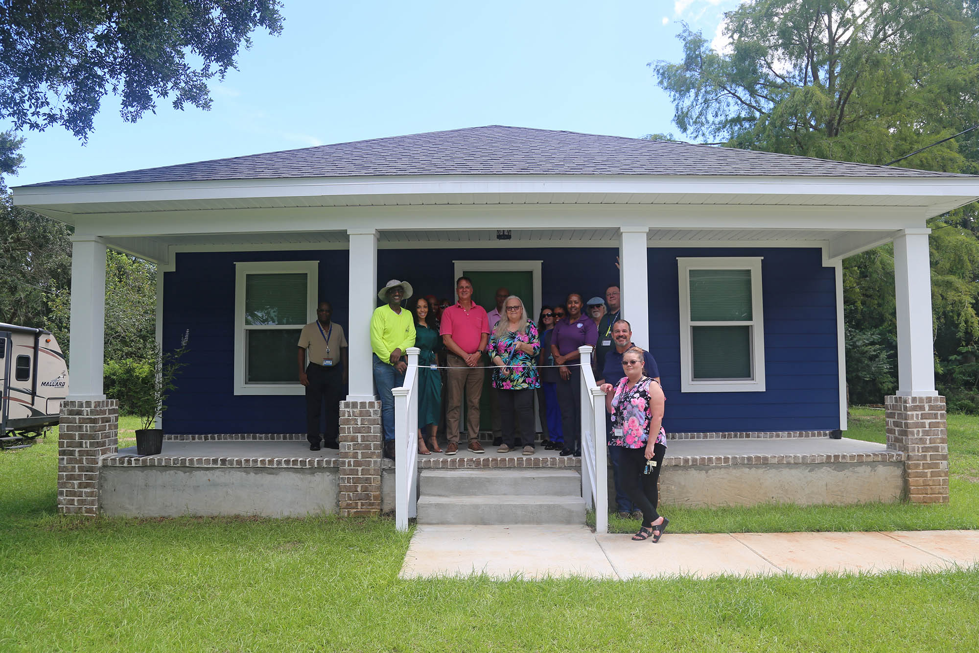 Emma Coker cuts the ribbon on her new home with county staff